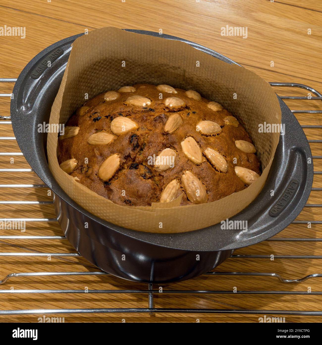 Petit gâteau Dundee, rond, fraîchement cuit, garni d'amandes, toujours dans un moule à pâtisserie doublé sur une grille de refroidissement. Banque D'Images