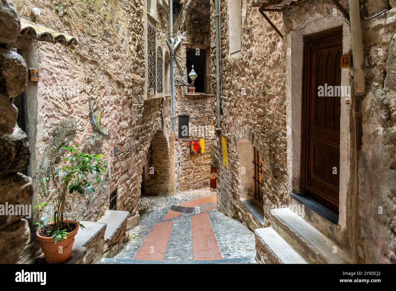 Une étroite ruelle pavée à flanc de colline serpentant le village médiéval historique de Dolceacqua, en Italie, dans la région de Ligurie. Banque D'Images