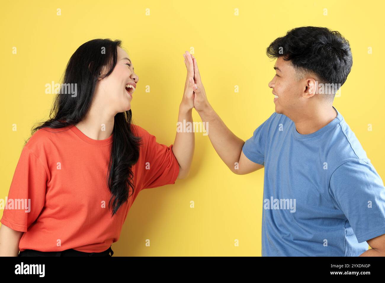 Deux personnes jeune ami asiatique Hi Five avec un visage heureux excité sur fond jaune Banque D'Images
