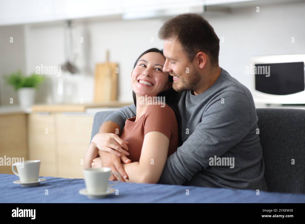 Heureux couple interracial flirtant dans la cuisine se regardant à la maison Banque D'Images