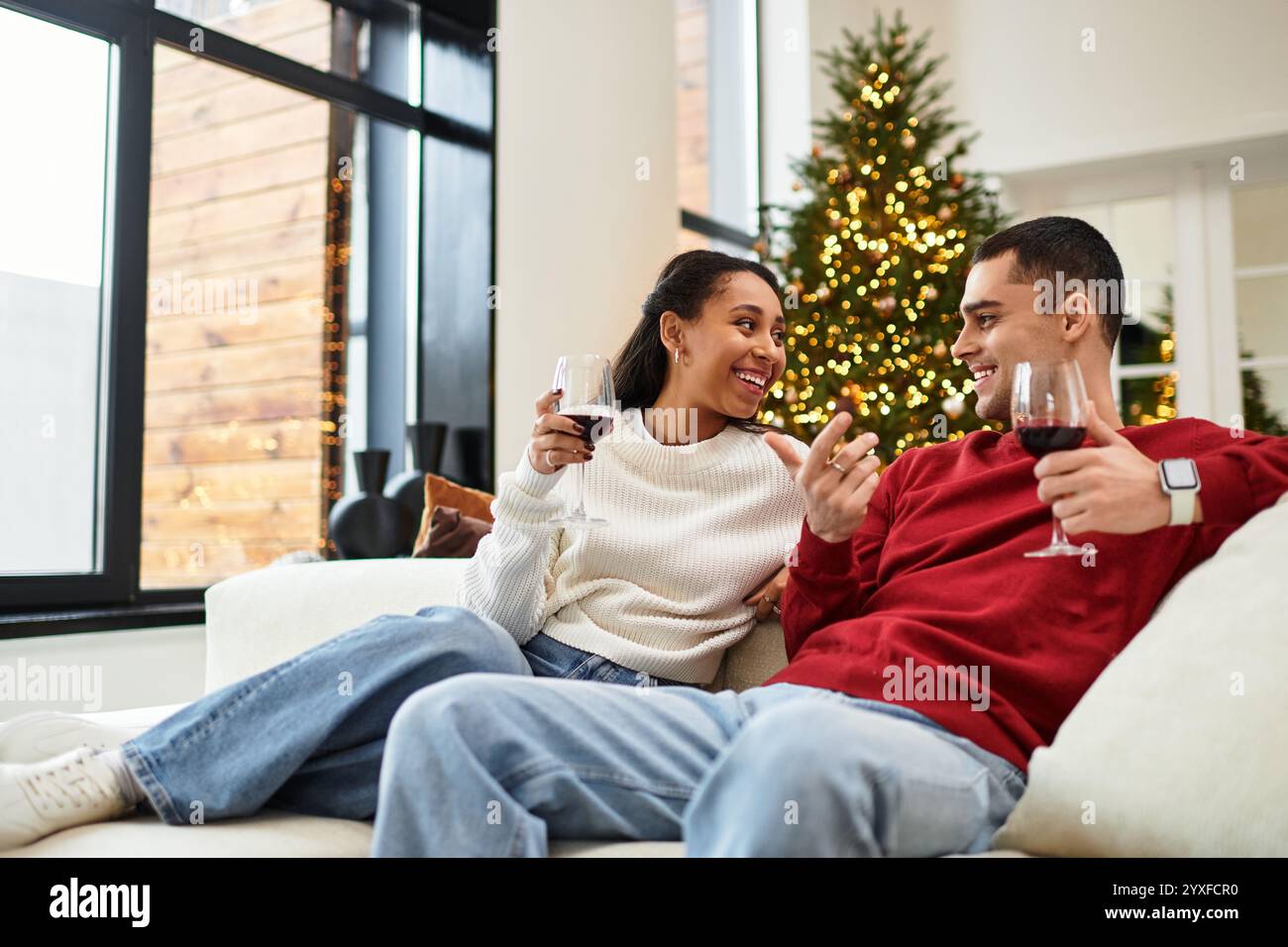 Un couple sirote du vin ensemble dans un cadre de Noël magnifiquement décoré. Banque D'Images
