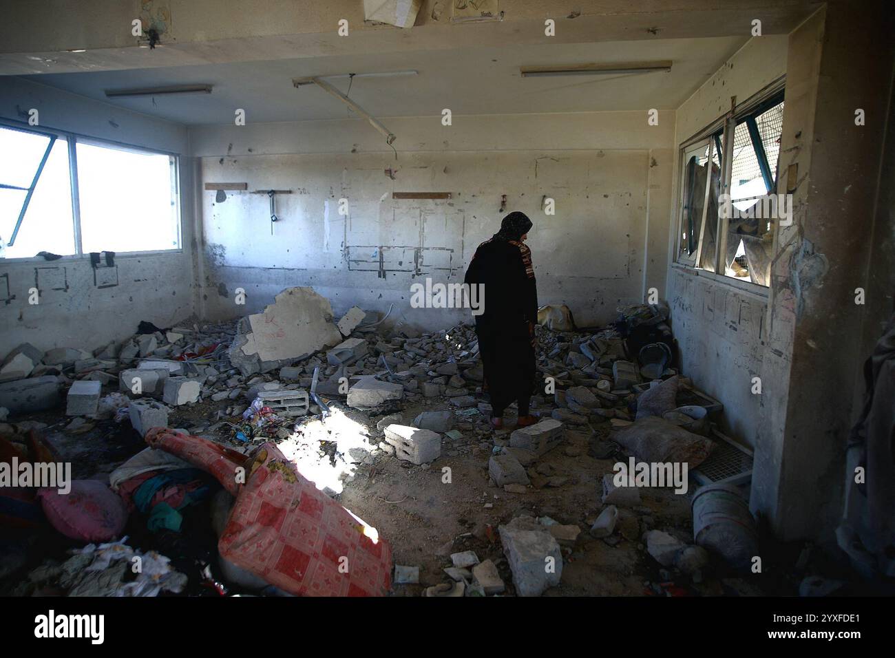 Khan Yunis, Palestine. 16 décembre 2024. Des Palestiniens inspectent les dégâts suite à une attaque de l’armée israélienne contre une école abritant des familles déplacées appartenant à l’Office de secours et de travaux des Nations Unies pour les réfugiés de Palestine dans le proche-Orient (UNRWA) à Khan Yunis, Gaza, bande de Gaza, territoire palestinien, le 16 décembre, 2024. photo de Ramez Habboub/ABACAPRESS. COM Credit : Abaca Press/Alamy Live News Banque D'Images