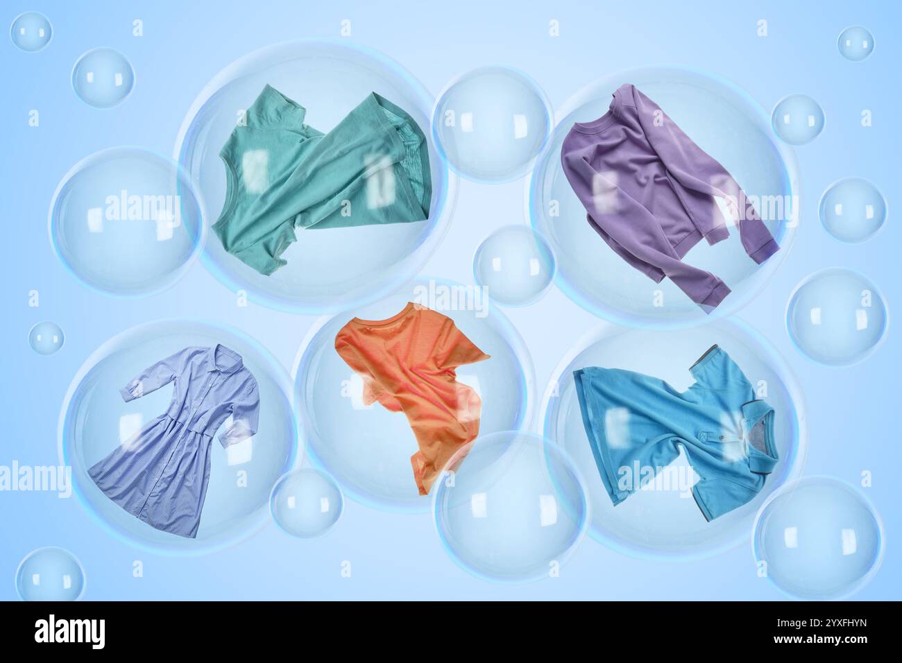 Plusieurs bulles de savon avec des vêtements à l'intérieur et vides flottant sur fond bleu clair. Blanchisserie jour Banque D'Images