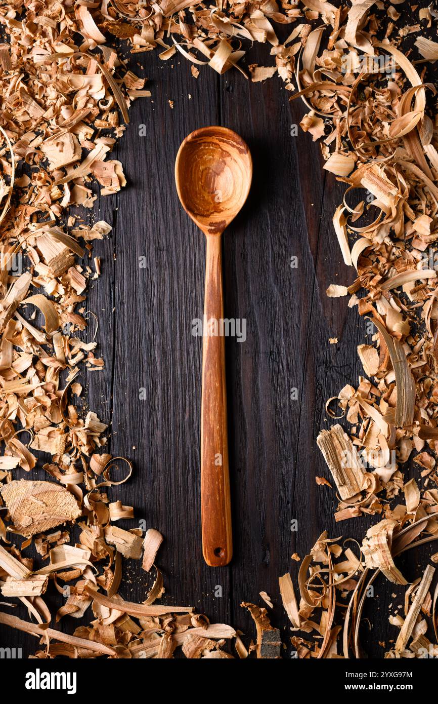 Cuillère en bois artisanale avec tas de limailles en bois de gros plan. Concept de fabrication artisanale Banque D'Images
