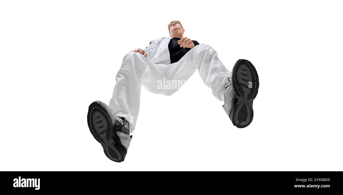 Image vue du bas d'un jeune homme à la mode en pantalon blanc et baskets noires, mettant en valeur l'énergie et le style sportif moderne. Confort et confiance Banque D'Images