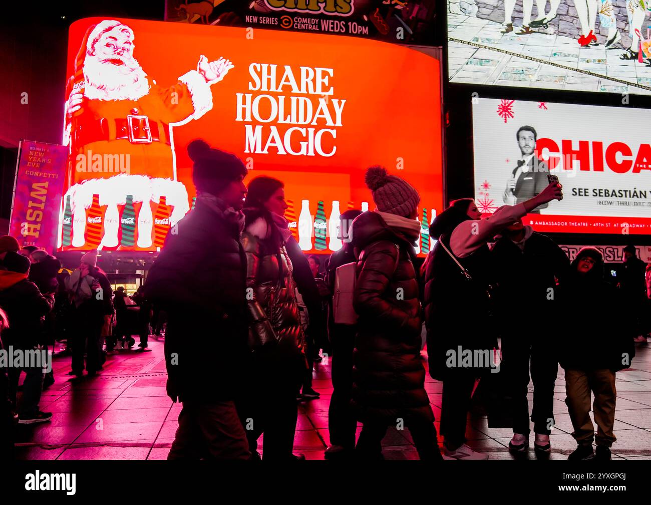 Les visiteurs de Times Square à New York le mercredi 4 décembre 2024 se promènent sous plusieurs panneaux d'affichage numériques sur le thème de Noël faisant la publicité de Coca-Cola. (© Richard B. Levine) Banque D'Images