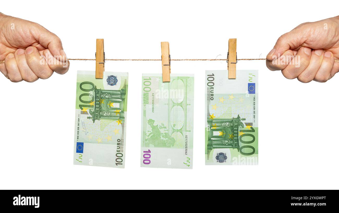Deux mains tiennent une ficelle avec des billets en euros coupés par des pinces à linge, représentant la gestion financière et les stratégies d'épargne. Banque D'Images