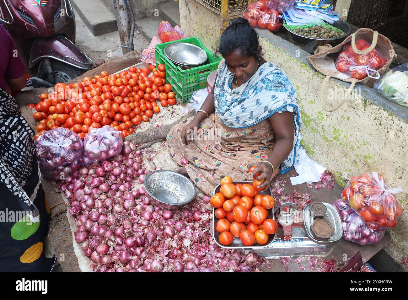 Vendeur utilisant des balances pour peser les tomates au marché aux légumes dans le district de Triplicane de Chennai, Tamil Nadu, Inde Banque D'Images