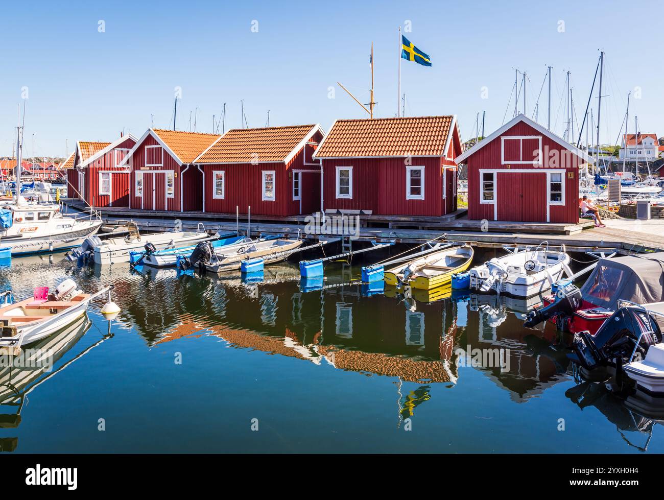 Cabanes rouges typiques dans le port invité de Skärhamn, en Suède, une marina populaire dans la province touristique de Bohuslän, entourée de bateaux amarrés. Banque D'Images