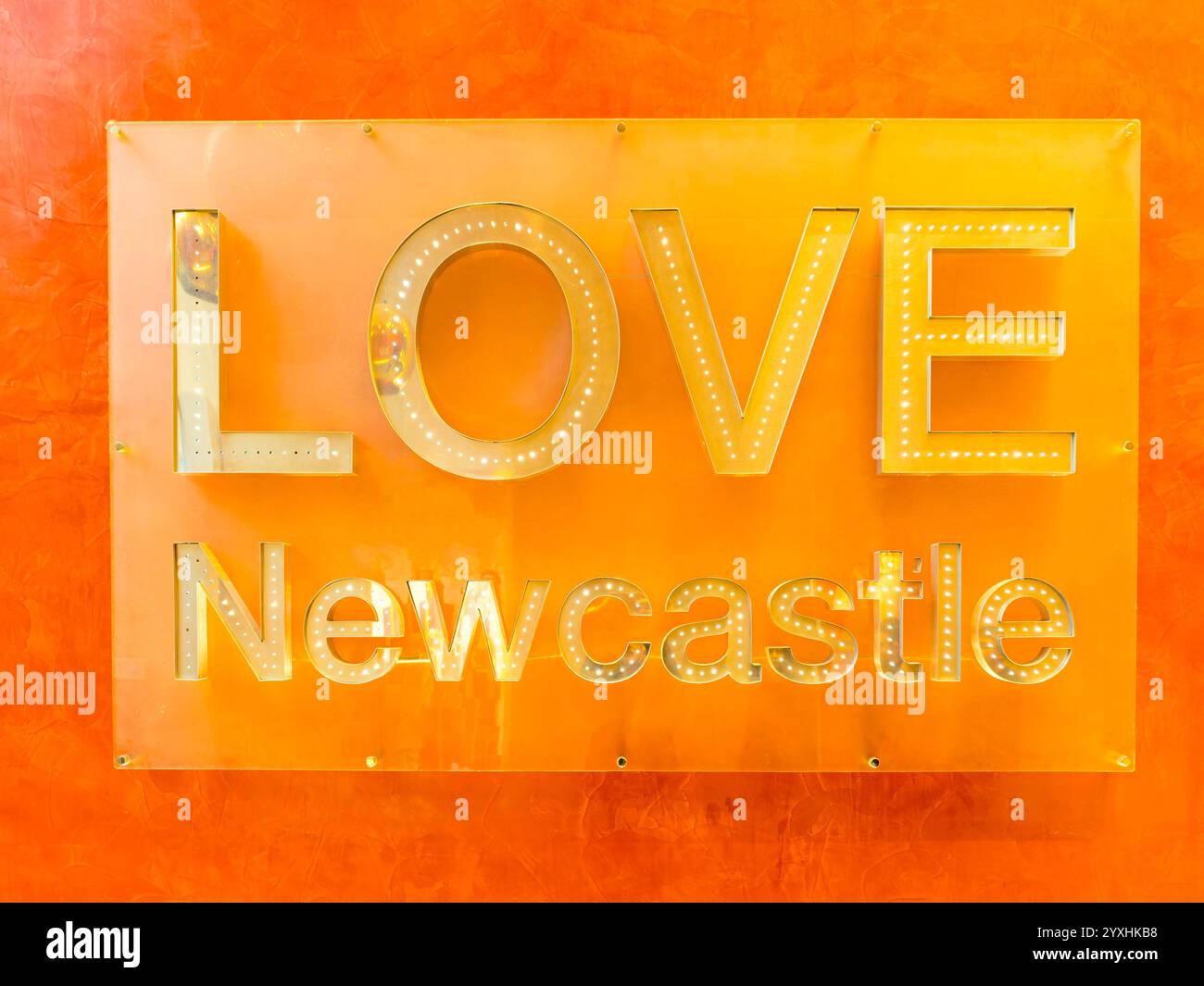 Un mur orange avec un panneau « LOVE Newcastle », soulignant la fierté locale et la vie urbaine Banque D'Images