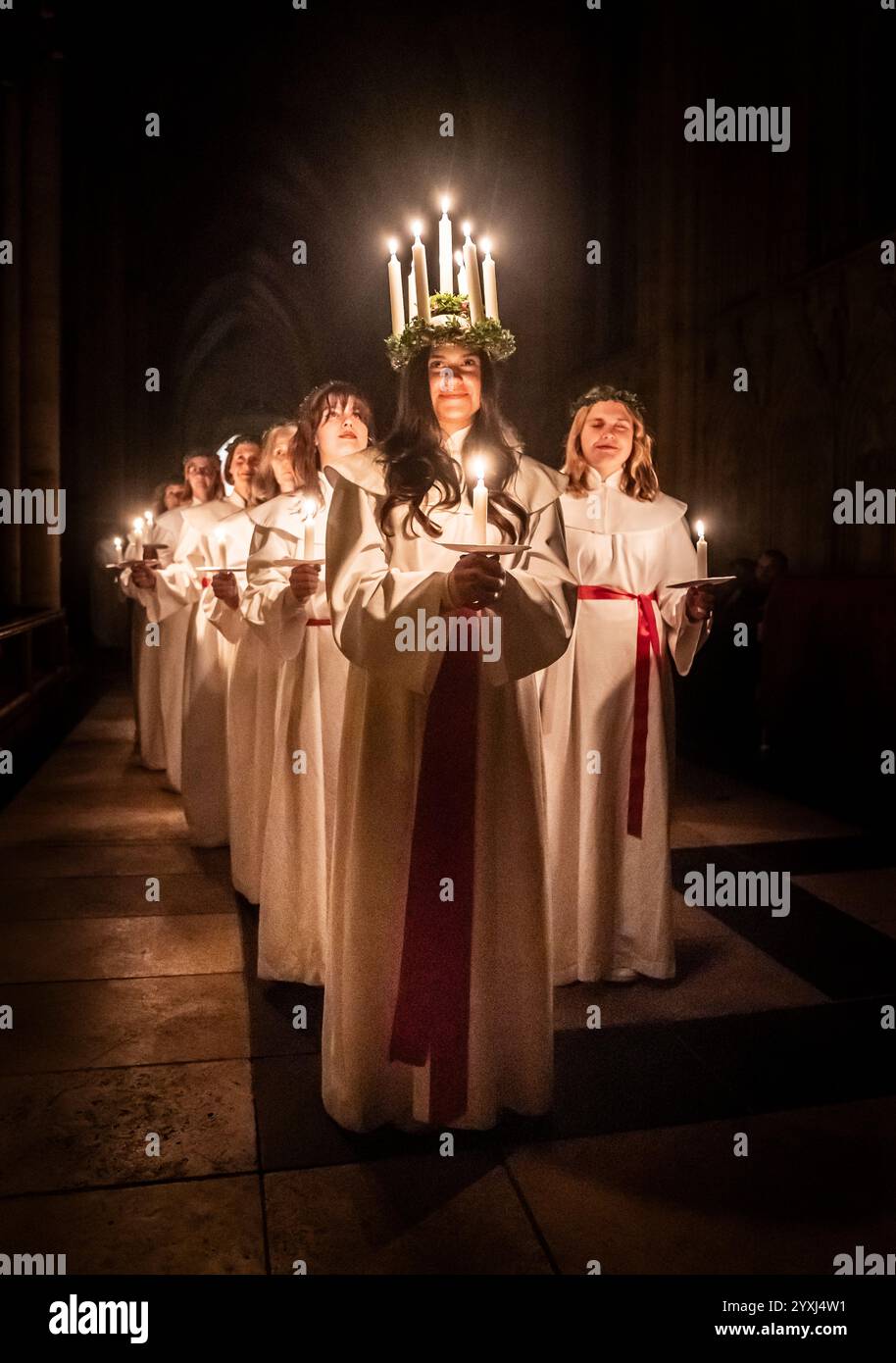 Alida Freding porte une couronne de bougies symbolisant Sainte Lucy alors qu'elle dirige la célébration de Sankta Lucia : Festival of Light at York Minster, basée sur la bravoure et le martyre d'une jeune fille sicilienne Sainte Lucy décédée au début du IVe siècle. Le service est géré en partenariat entre York Minster et York Anglo-Scandinavian Society (YASS). Date de la photo : lundi 16 décembre 2024. En Suède, Lucie est l'une des traditions les plus importantes du calendrier, symbole et célébration de la lumière et partie de la saison de l'Avent. Son nom et son histoire ont atteint la Suède avec Christianisme et elle rema Banque D'Images