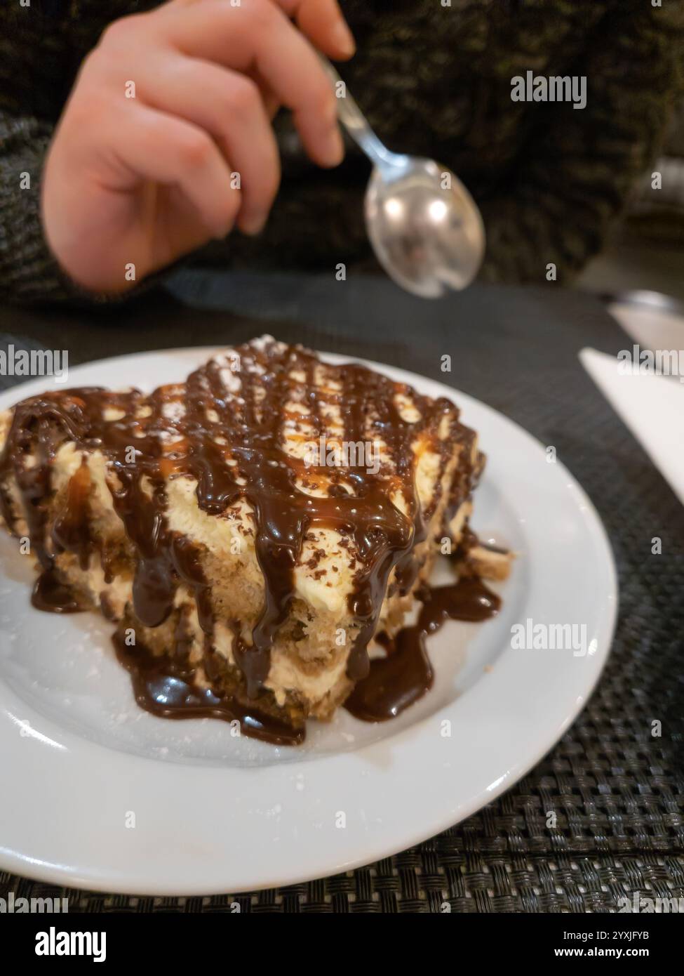 Manger du tiramisu avec garniture de chocolat. Main tenant une cuillère Banque D'Images