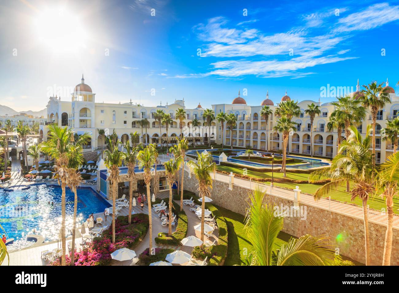 Un bel hôtel avec piscine et palmiers. La piscine est entourée de chaises longues et de parasols Banque D'Images