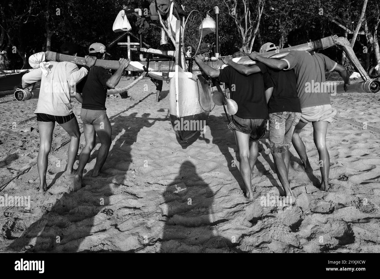 Les pêcheurs travaillent ensemble pour soulever leurs bateaux loin du rivage, après être revenus de la pêche sur la plage de Papuma. Banque D'Images
