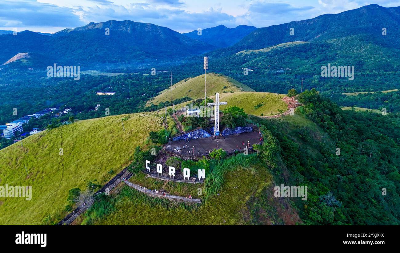 Une vue emblématique du mont Tapyas à Coron, Philippines, mettant en valeur le célèbre monument de croix au sommet de collines verdoyantes. Cette superbe prise de vue aérienne met en valeur Banque D'Images