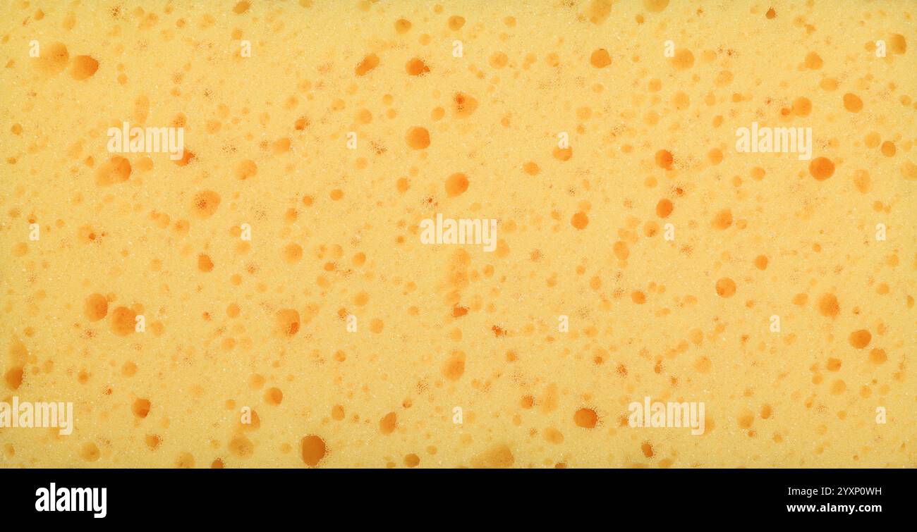 Vue rapprochée d'une éponge de nettoyage jaune, soulignant sa texture poreuse, créant un fond texturé abstrait idéal pour le nettoyage et l'hygiène co Banque D'Images
