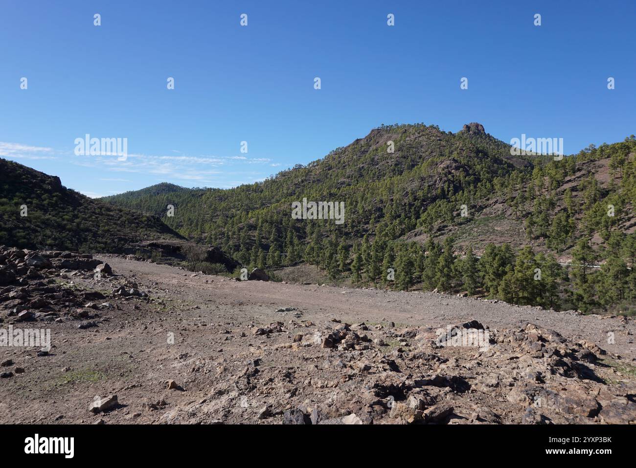 Un paysage rocheux et aride avec un ciel bleu clair. Le ciel est parsemé de nuages, mais ils sont éloignés et n'obscurcissent pas la vue. Le paysage est m Banque D'Images