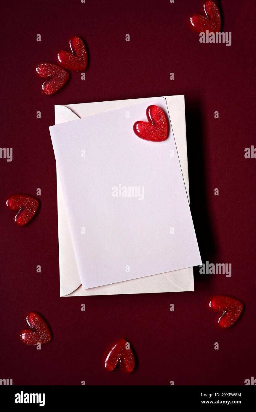 Enveloppe et coeurs rouges sur fond rouge. Vue de dessus. Saint-Valentin. Banque D'Images