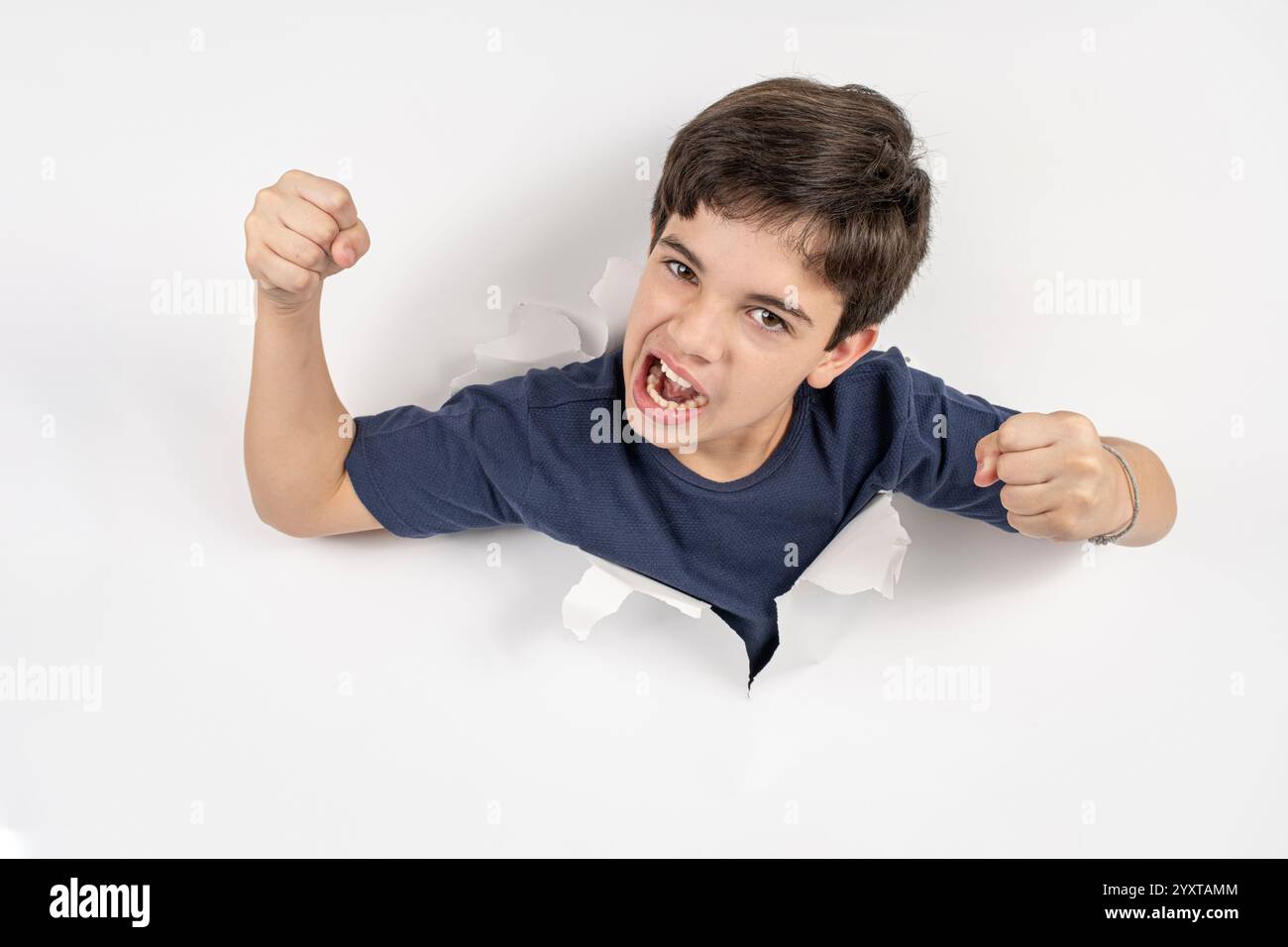 Enfant brésilien de 11 ans avec son corps à travers un carton blanc et les poings serrés. Banque D'Images