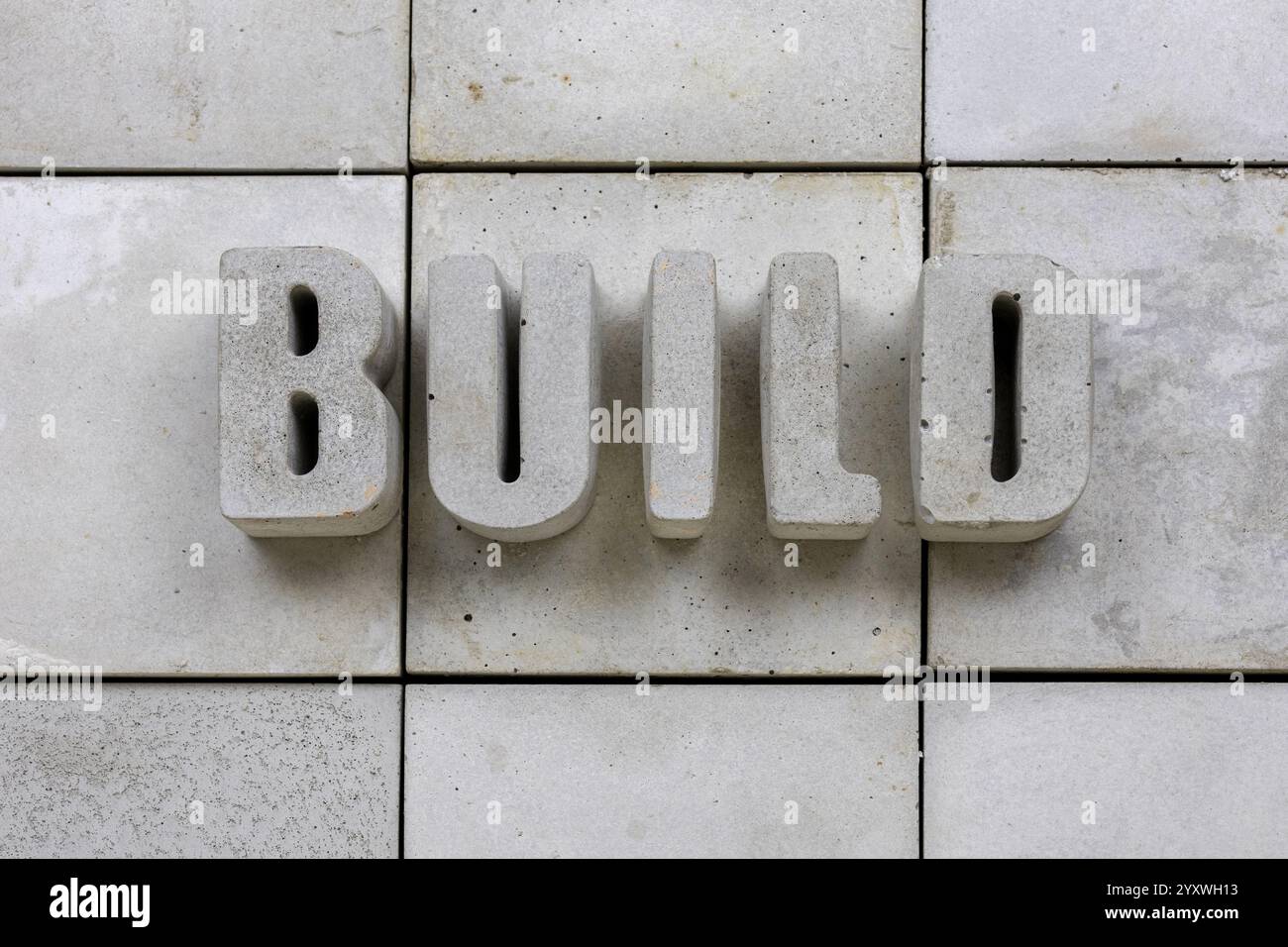 Mot CONSTRUIRE dans des lettres concrètes sur fond carrelé béton Nice espace de copie Banque D'Images