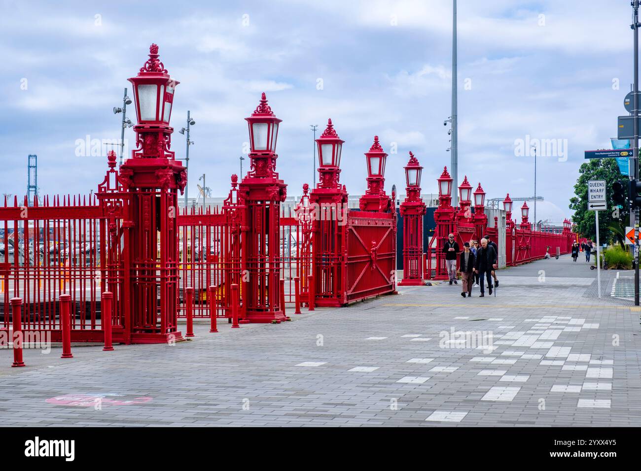 Les gens marchent le long de la clôture rouge sur le trottoir de Quay St, Queens Wharf, Auckland Harbourfront, Nouvelle-Zélande Banque D'Images