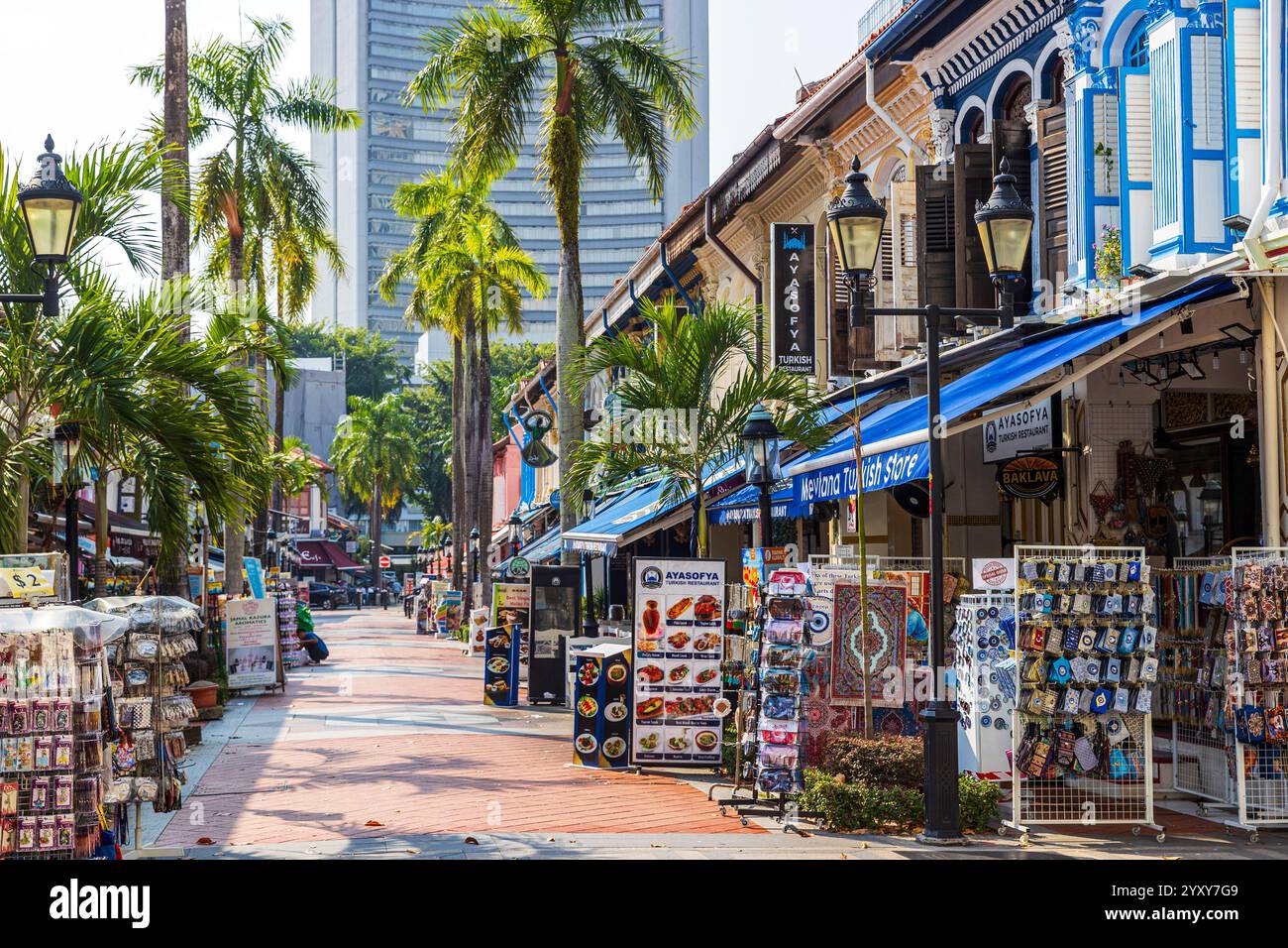 Des étals de marché colorés et des magasins remplis de souvenirs et d'accessoires divers dans une zone commerçante extérieure ensoleillée dans le quartier de Kampong Glam, Singapour. Banque D'Images