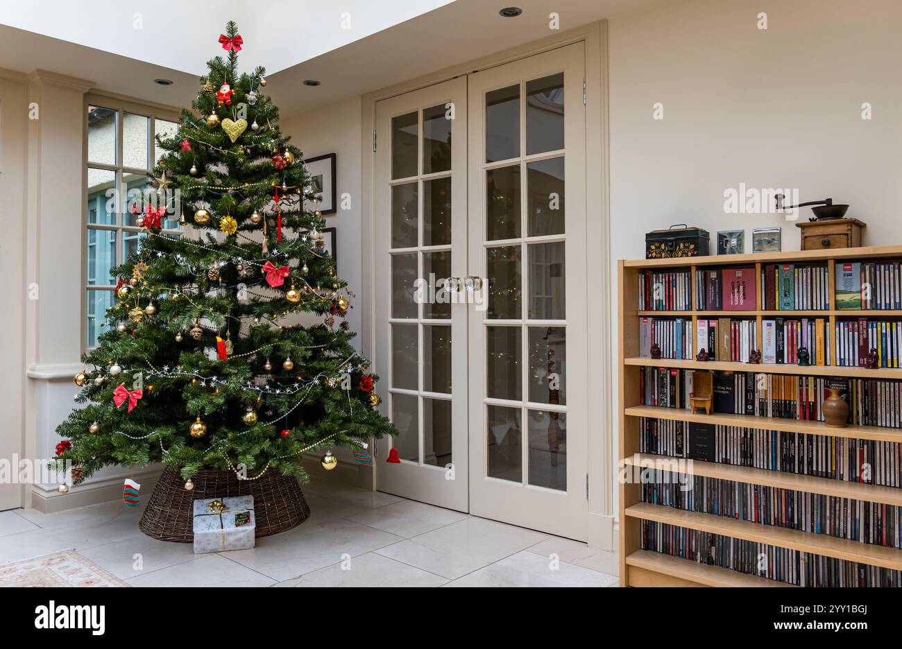 Intérieur de la maison avec arbre de Noël décoré et présent sous l'arbre dans le conservatoire du salon, Royaume-Uni Banque D'Images