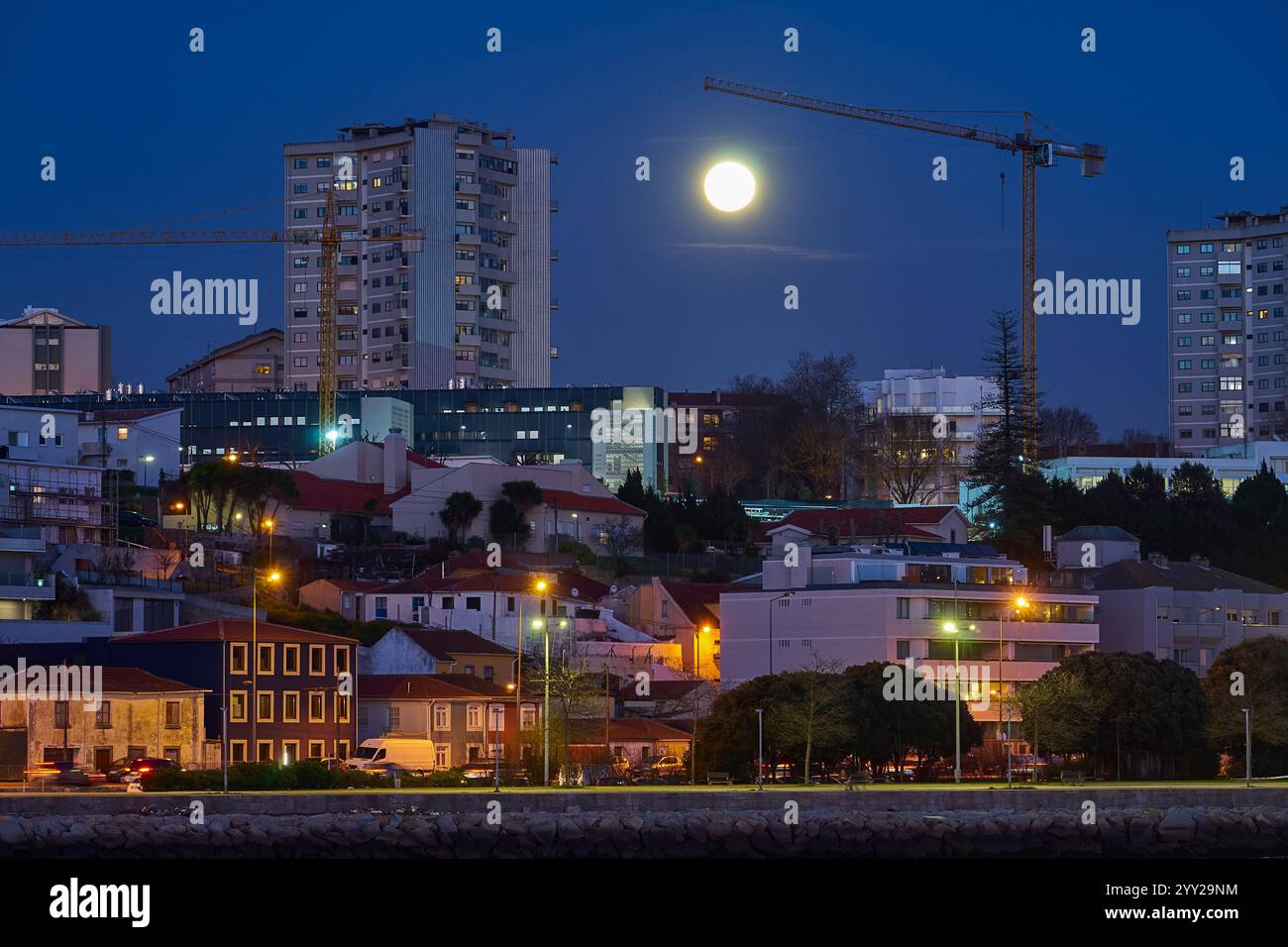 Pleine lune au-dessus du paysage urbain avec des grues et grues la nuit Banque D'Images