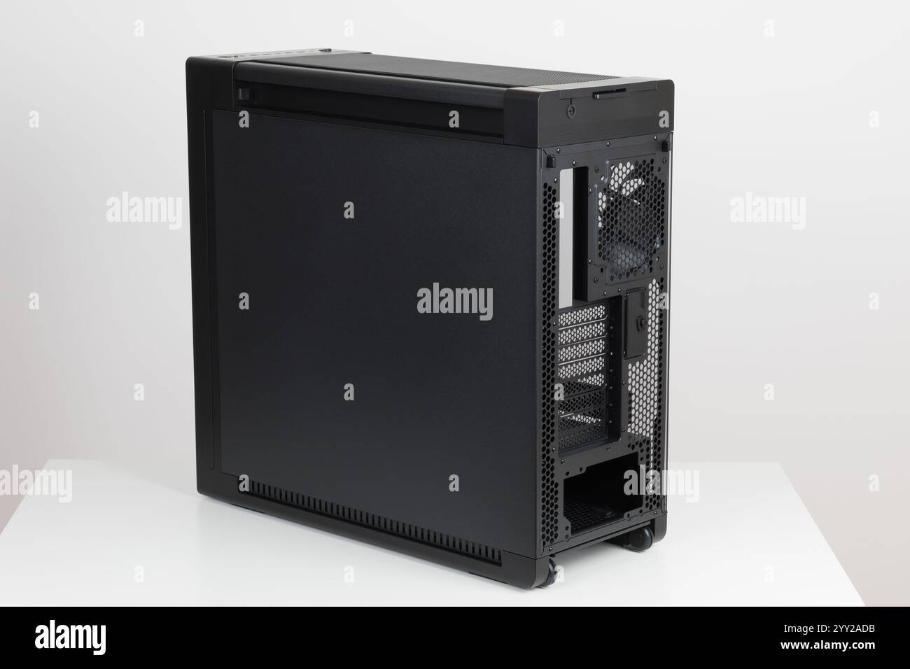Face arrière de la grosse tour vide boîtier d'ordinateur, châssis , manœuvre sans effort avec deux roues intégrées sur fond blanc. En bas se trouve un endroit Banque D'Images