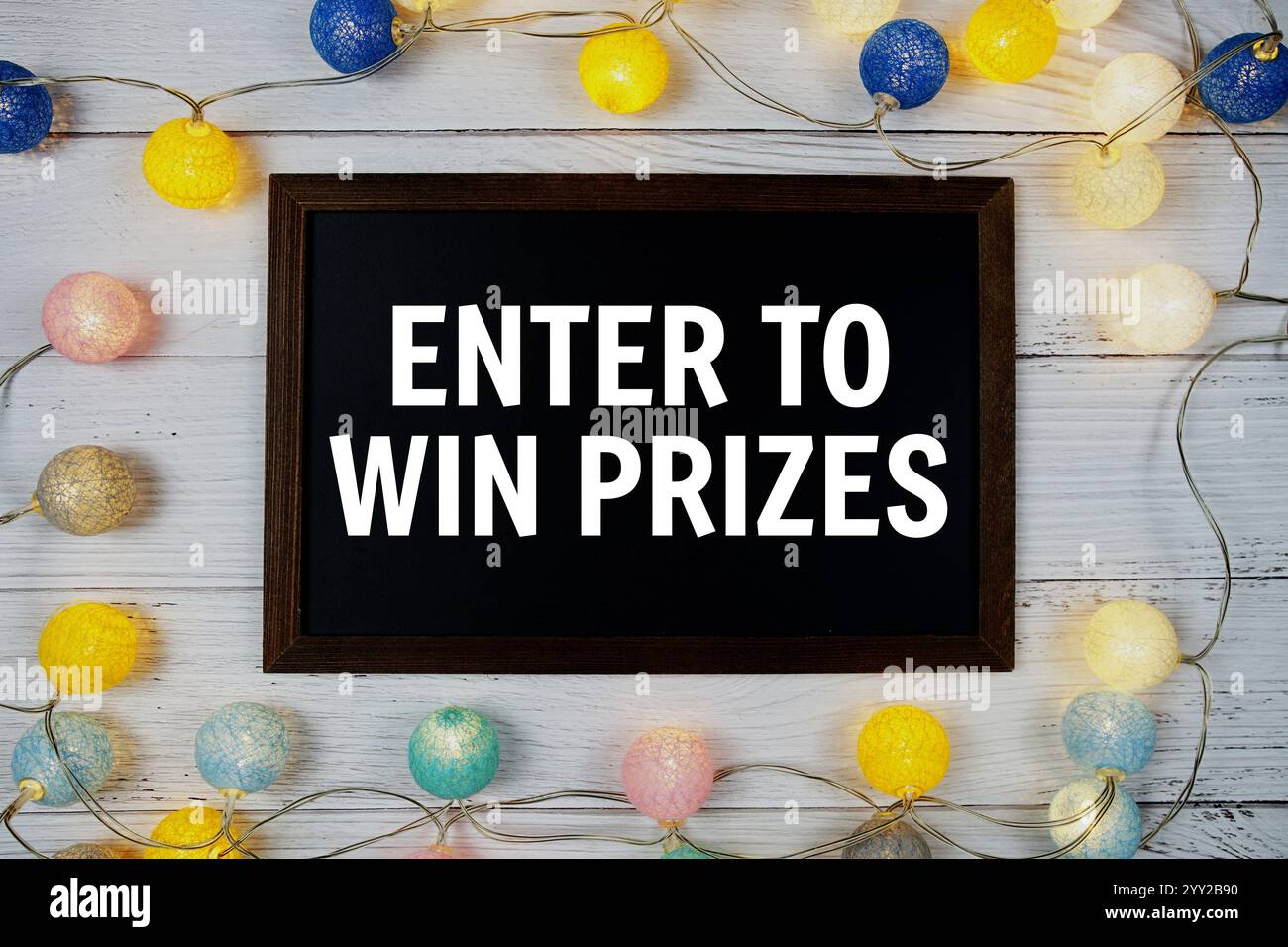 Entrez pour gagner des prix texte écrit sur tableau noir avec décoration de boules de coton LED sur fond en bois Banque D'Images
