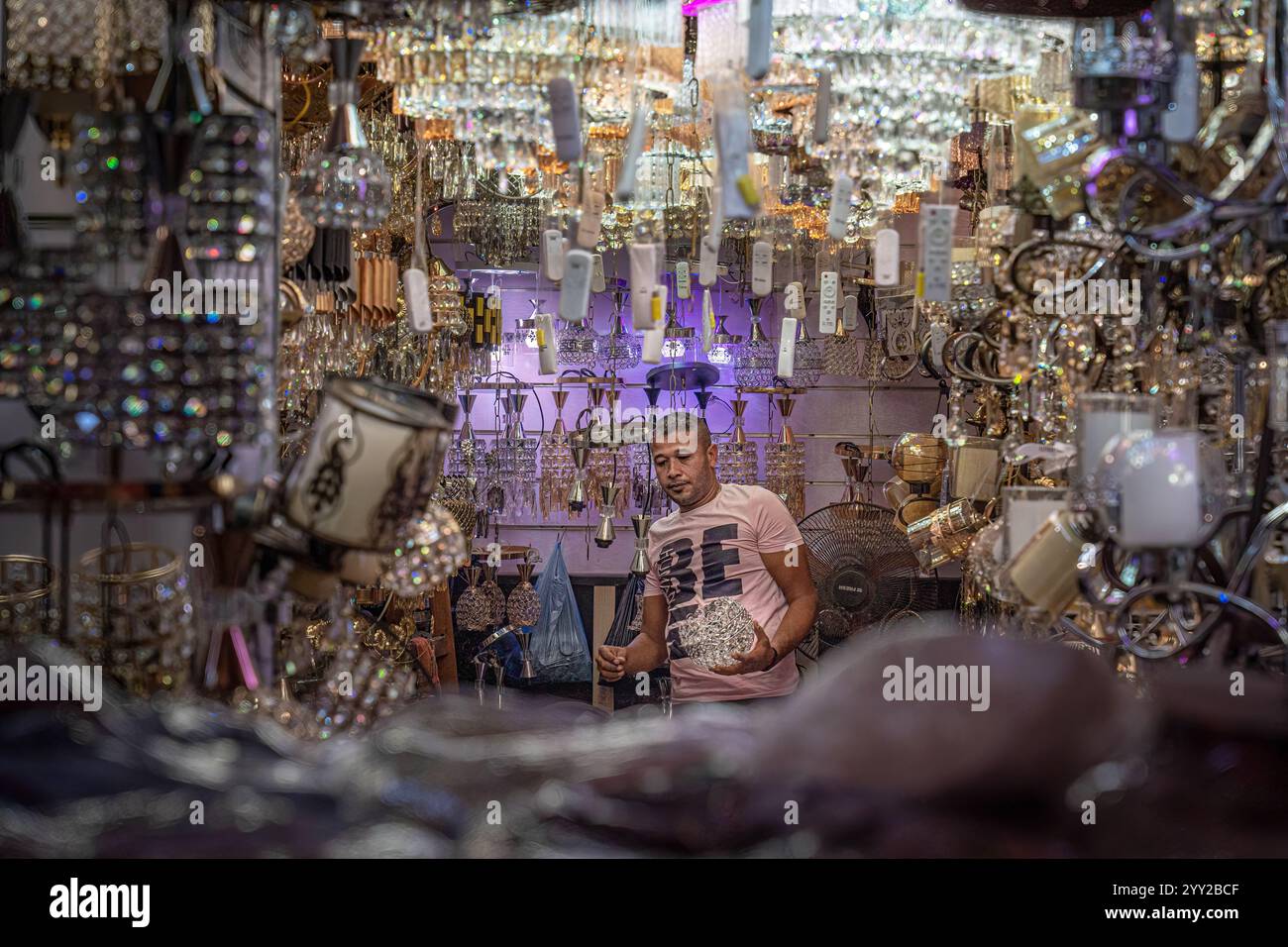 Un magasin d'éclairage décoratif à Alexandrie, en Égypte, avec des lustres ornés et des lampes en cristal exposés. Un homme examine les lumières dans la boutique vibrante. Banque D'Images