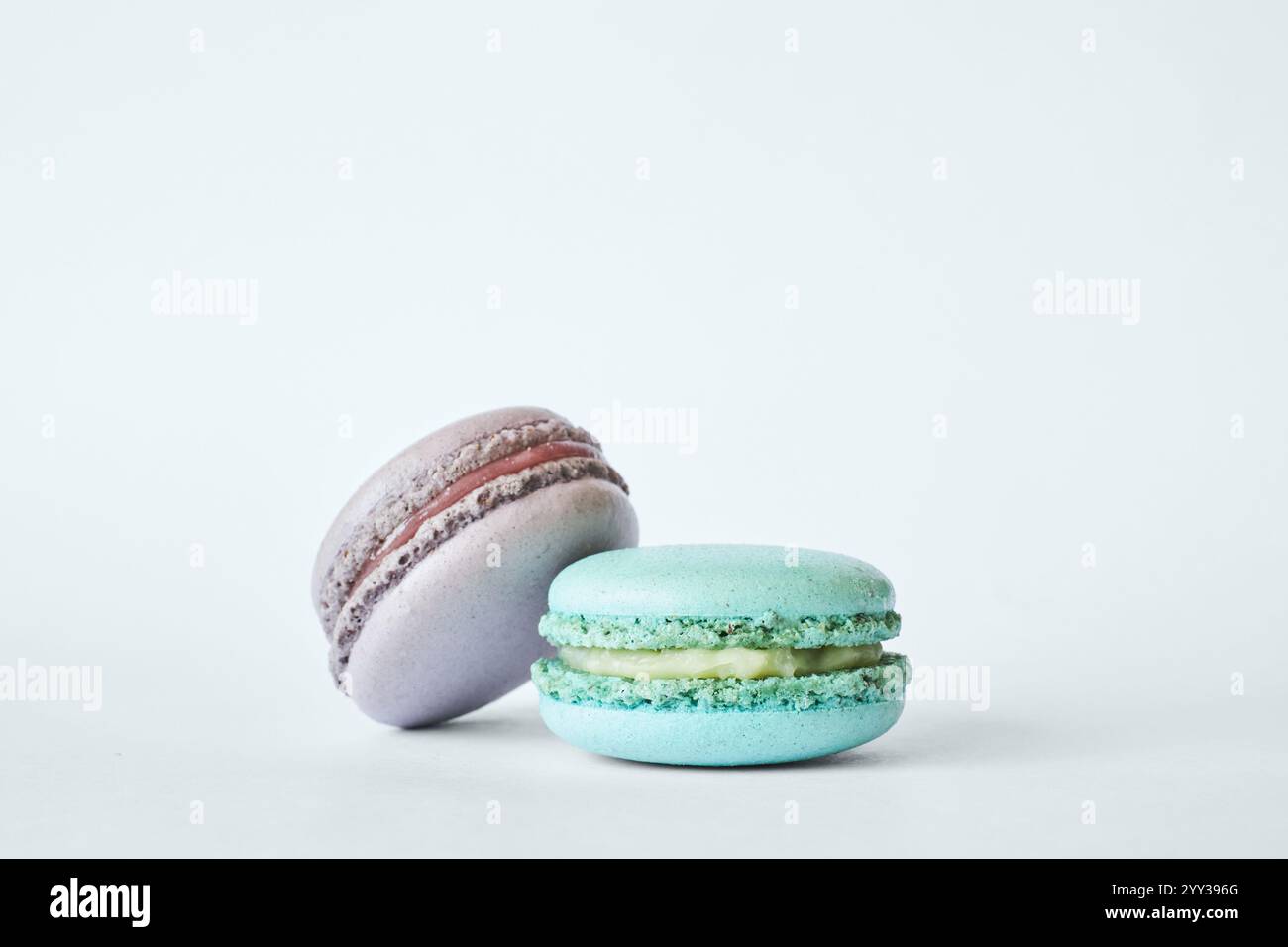 Deux macarons français colorés, des gâteaux aux saveurs différentes, menthe, pomme, saveur de cassis. dessert, macarons aigue-marine, vert, couleur pourpre. Copier spac Banque D'Images