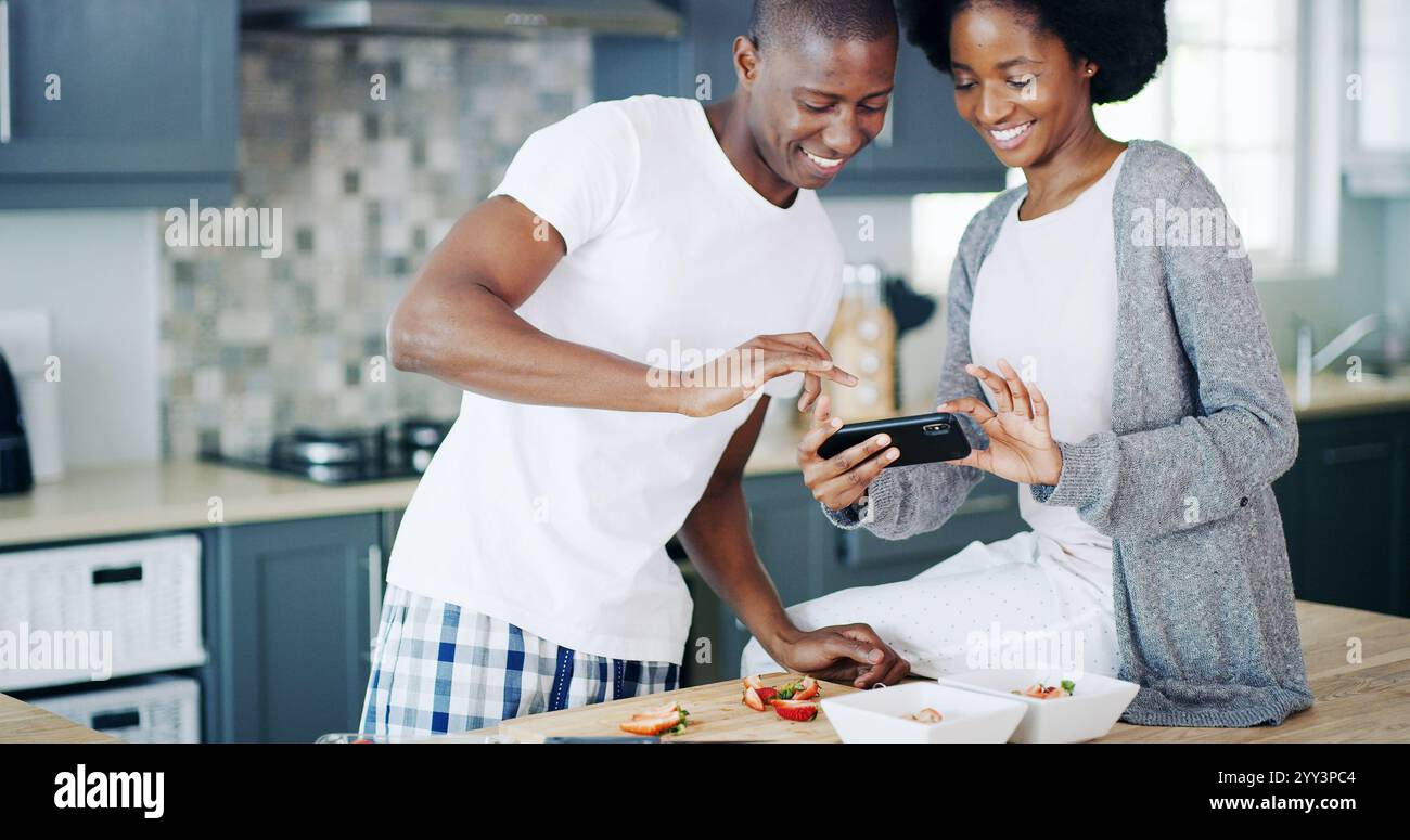 Couple heureux, petit déjeuner et photo en cuisine pour manger salade de fruits ou détox à la maison ou à la maison. Peuple africain, sourire ou image de nourriture Banque D'Images