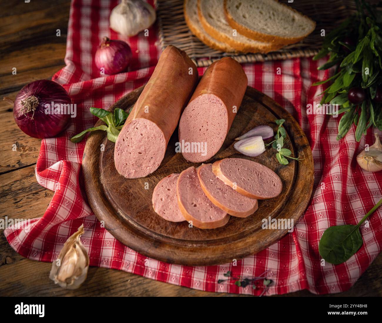 Fromage de tête tranché avec oignons rouges, ail, herbes et pain sur planche de bois rustique Banque D'Images