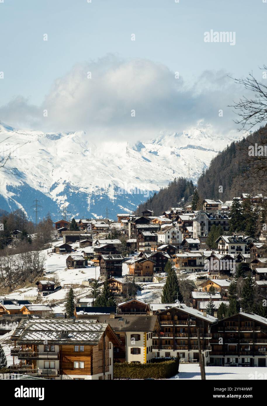 Un pittoresque village suisse niché sous un paysage alpin enneigé, présente de charmants chalets sur fond de sommets majestueux. Banque D'Images