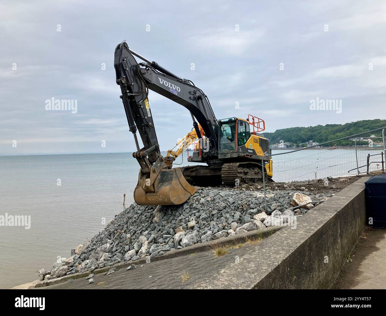 Une excavatrice Volvo stationnée au-dessus de rochers et de gravats au bord de la mer, qui fait partie du projet de protection côtière de Mumbles par Knights Brown. 12 juin 2023. - Image de stock capturée avec un smartphone