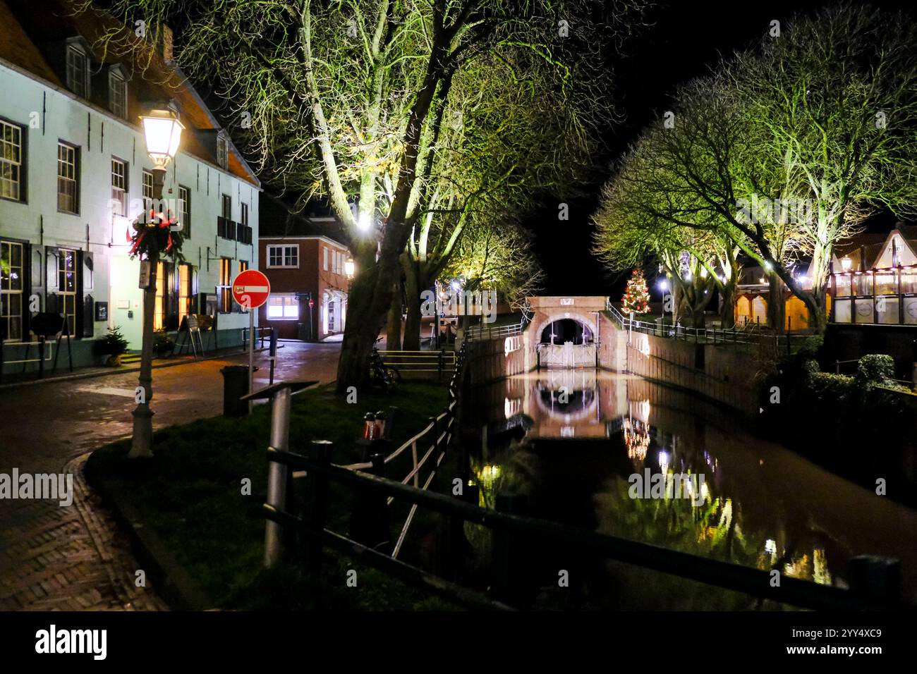 DEU, Deutschland, Niedersachsen, Krummhörn, Greetsiel, 12.12.2024 : das beleuchtete Siel mit alter Schleuse und dem Hohen Haus auf der linken Seite in Banque D'Images