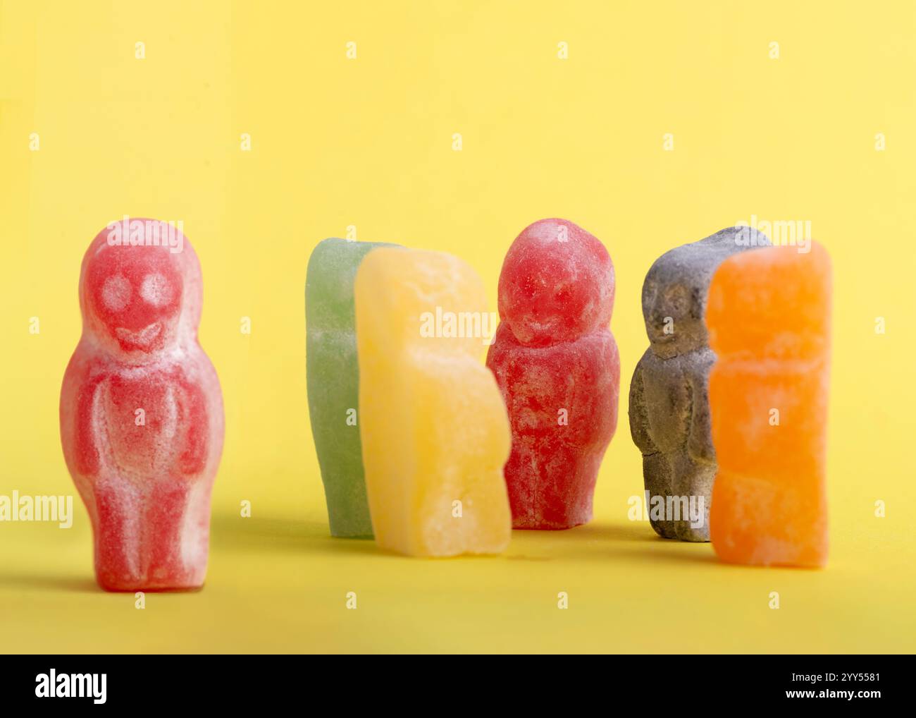red jelly baby se distingue, face à un groupe de bonbons multicolores apparemment connectés. L'image évoque des sentiments de solitude, aspirant à se connecter Banque D'Images