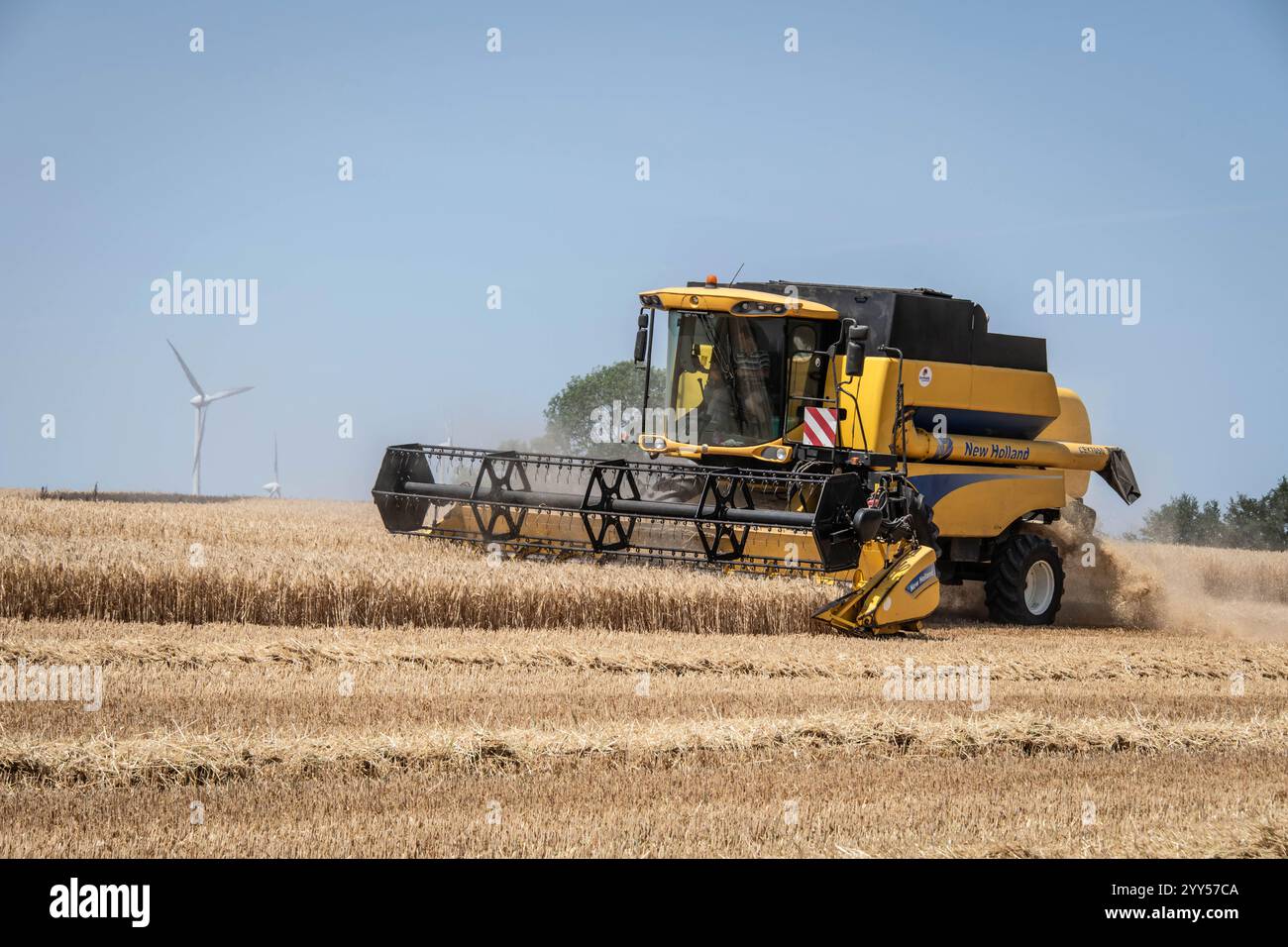 Péré-Saint-Pierre-la-noue, plaine de l'Aunis (centre-ouest de la France) : moissonneuse-batteuse dans un champ d'orge devant des éoliennes sous le soleil de juin, A. Banque D'Images