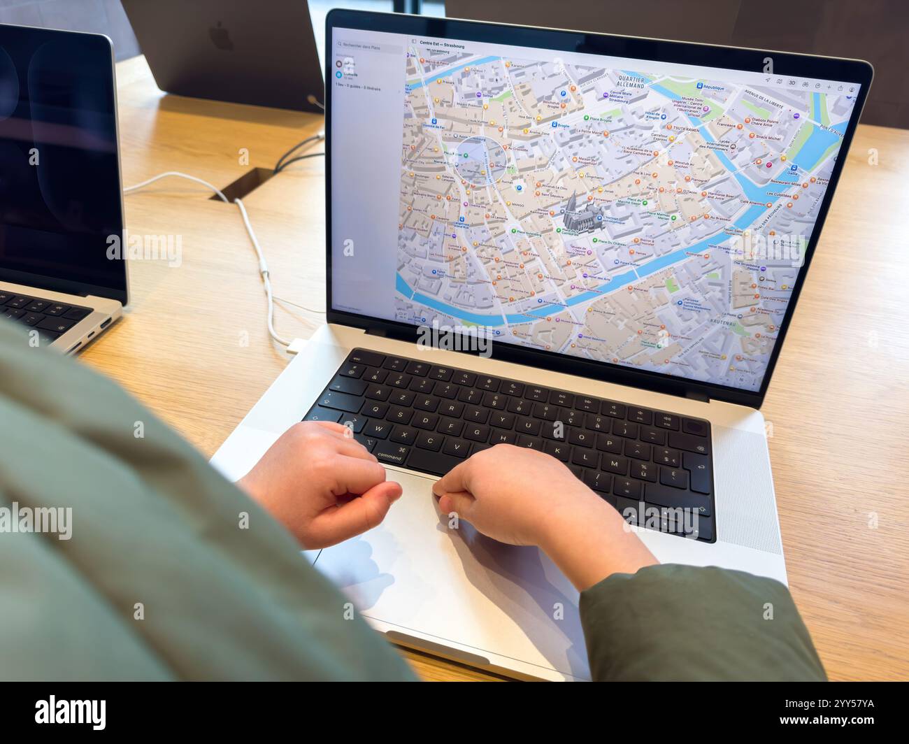 Paris, France - 10 décembre 2024 : un tout-petit interagit avec le nouveau MacBook Pro équipé de la puce en silicium M4, explorant un plan de la ville sur son écran vibrant dans un Apple Store. Banque D'Images