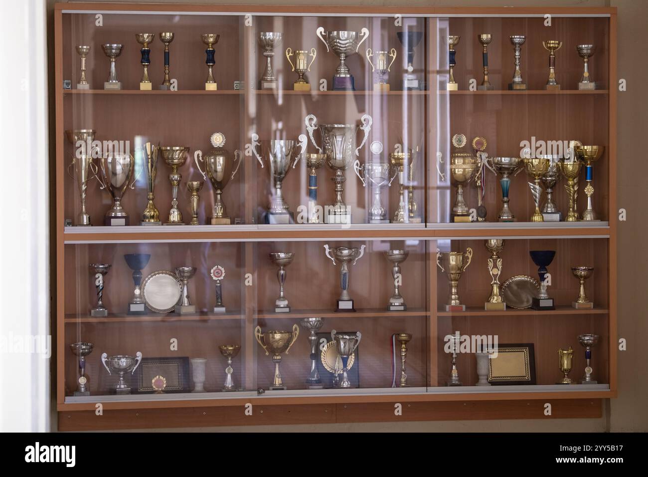 Étagère de vitrine de trophée en verre et en bois pleine de trophées d'or et d'argent, de récompenses et de tasses. Banque D'Images