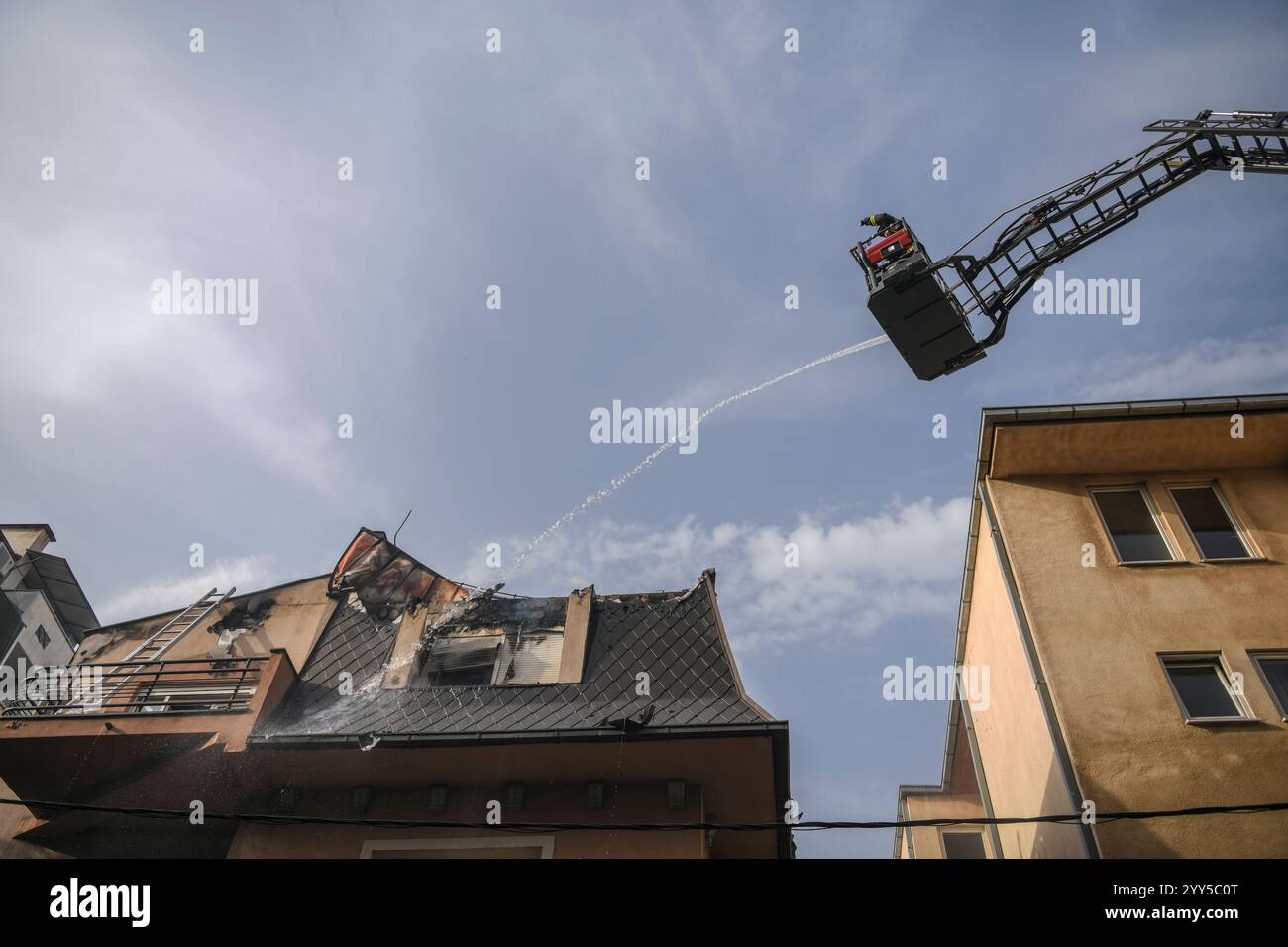 Scène dramatique de pompiers s'élevant sur une grue à échelle coulissante mécanique à l'épicentre de l'incendie. Grue à flèche avec pompiers Banque D'Images