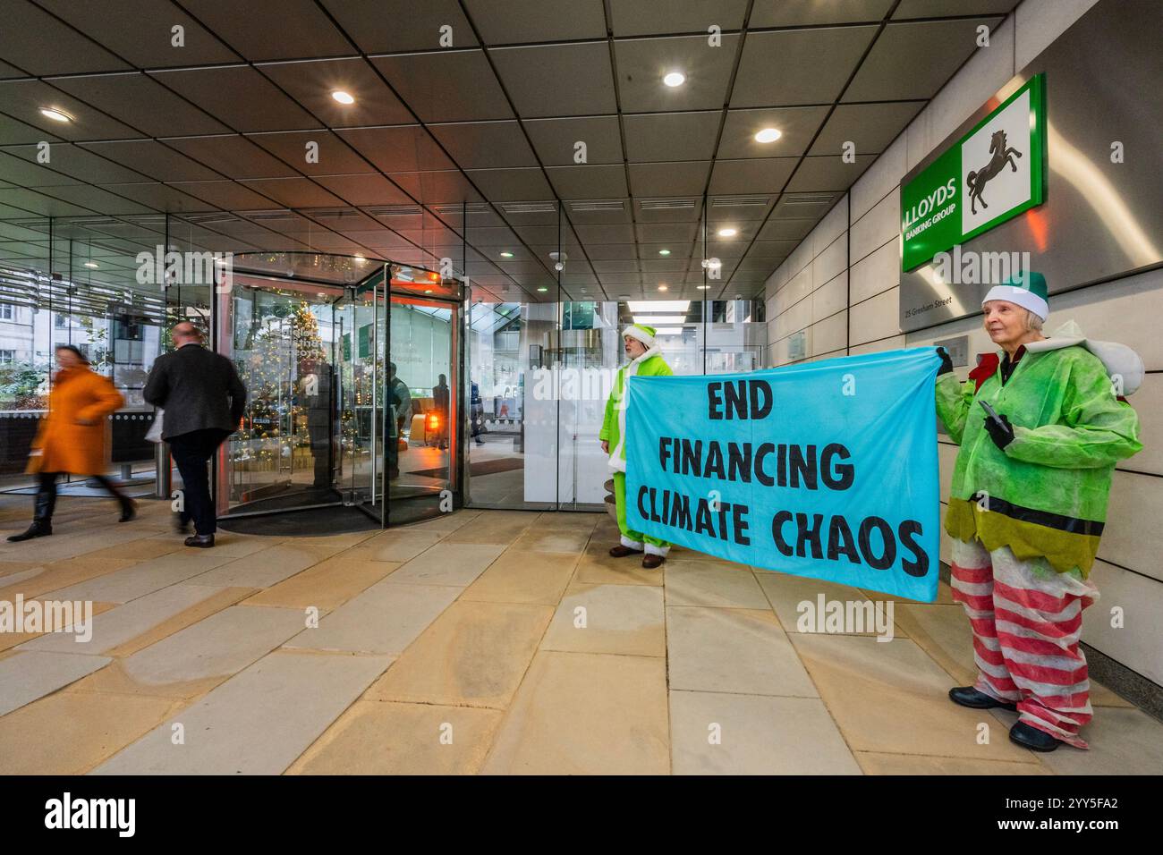 Londres, Royaume-Uni. 19 décembre 2024. Une rébellion d'extinction Green Santa et ses elfes piquèrent l'entrée principale et distribuèrent des tracts pour demander à Lloyds Bank de «nettoyer leur acte!» et pour mettre fin au financement du chaos climatique. Les manifestants pensent que Lloyds pourrait être un leader sur le climat, mais « ne prennent pas les mesures nécessaires ». La manifestation a eu lieu devant le siège de la Banque à Gresham Street, dans la ville de Londres. Crédit : Guy Bell/Alamy Live News Banque D'Images