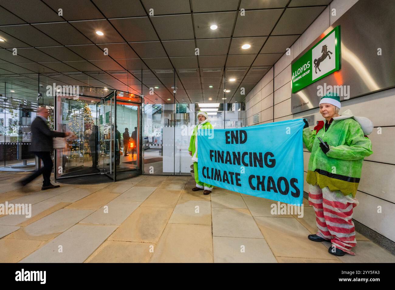 Londres, Royaume-Uni. 19 décembre 2024. Une rébellion d'extinction Green Santa et ses elfes piquèrent l'entrée principale et distribuèrent des tracts pour demander à Lloyds Bank de «nettoyer leur acte!» et pour mettre fin au financement du chaos climatique. Les manifestants pensent que Lloyds pourrait être un leader sur le climat, mais « ne prennent pas les mesures nécessaires ». La manifestation a eu lieu devant le siège de la Banque à Gresham Street, dans la ville de Londres. Crédit : Guy Bell/Alamy Live News Banque D'Images