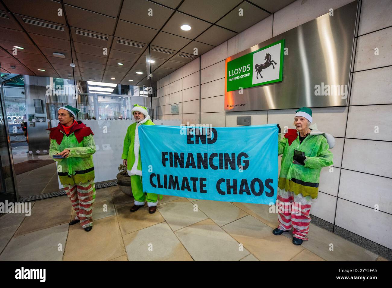 Londres, Royaume-Uni. 19 décembre 2024. Une rébellion d'extinction Green Santa et ses elfes piquèrent l'entrée principale et distribuèrent des tracts pour demander à Lloyds Bank de «nettoyer leur acte!» et pour mettre fin au financement du chaos climatique. Les manifestants pensent que Lloyds pourrait être un leader sur le climat, mais « ne prennent pas les mesures nécessaires ». La manifestation a eu lieu devant le siège de la Banque à Gresham Street, dans la ville de Londres. Crédit : Guy Bell/Alamy Live News Banque D'Images