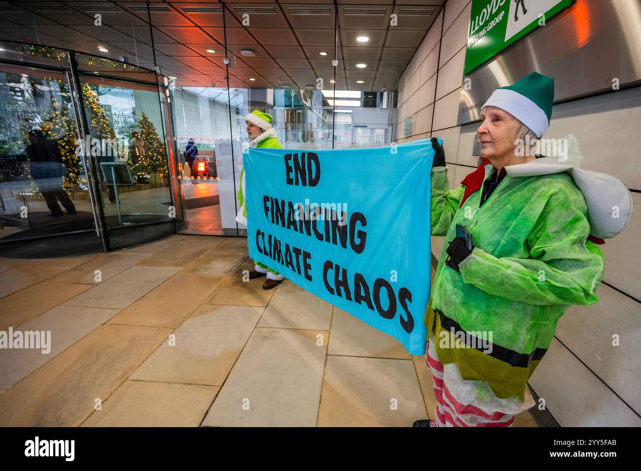 Londres, Royaume-Uni. 19 décembre 2024. Une rébellion d'extinction Green Santa et ses elfes piquèrent l'entrée principale et distribuèrent des tracts pour demander à Lloyds Bank de «nettoyer leur acte!» et pour mettre fin au financement du chaos climatique. Les manifestants pensent que Lloyds pourrait être un leader sur le climat, mais « ne prennent pas les mesures nécessaires ». La manifestation a eu lieu devant le siège de la Banque à Gresham Street, dans la ville de Londres. Crédit : Guy Bell/Alamy Live News Banque D'Images