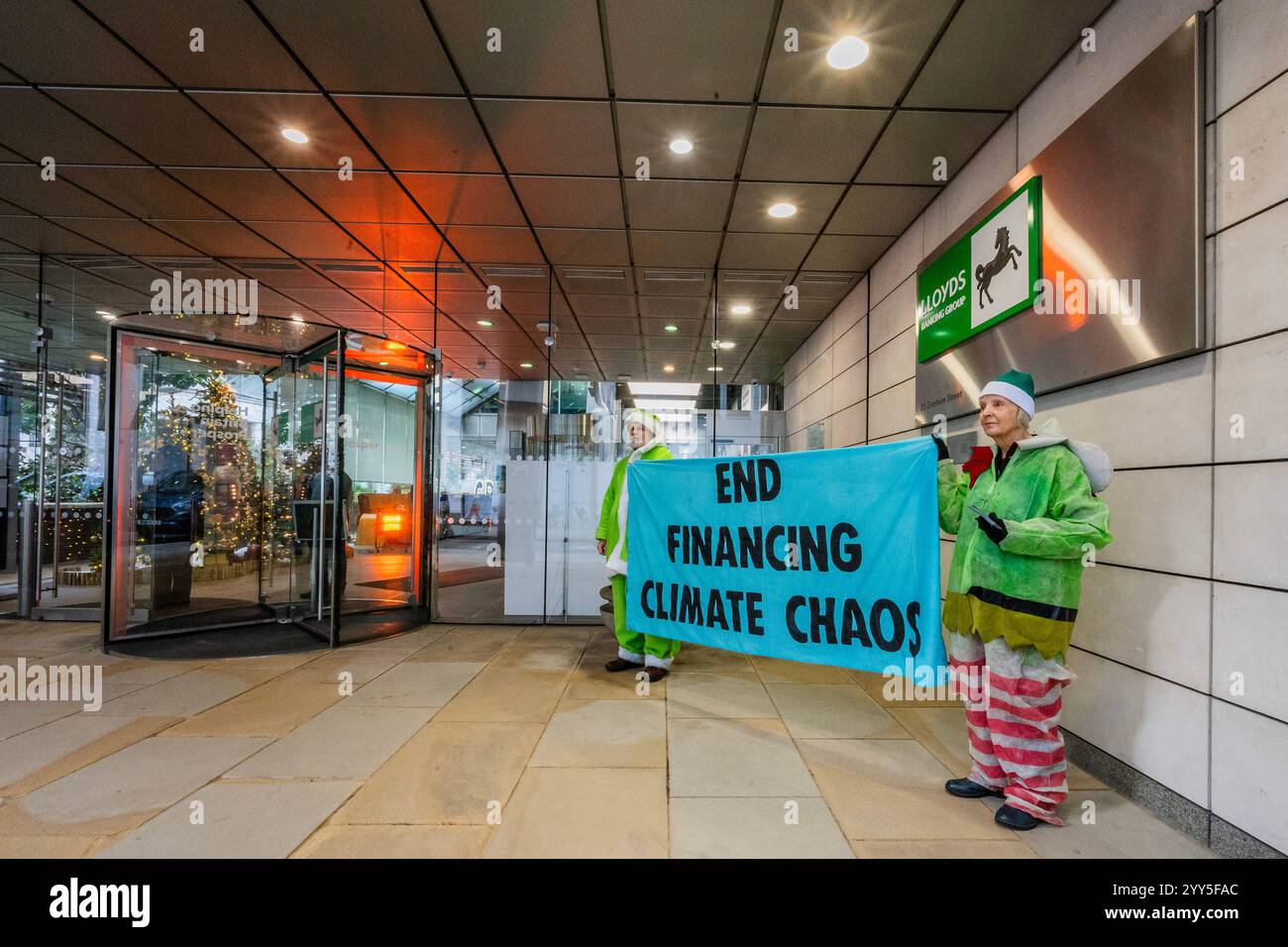 Londres, Royaume-Uni. 19 décembre 2024. Une rébellion d'extinction Green Santa et ses elfes piquèrent l'entrée principale et distribuèrent des tracts pour demander à Lloyds Bank de «nettoyer leur acte!» et pour mettre fin au financement du chaos climatique. Les manifestants pensent que Lloyds pourrait être un leader sur le climat, mais « ne prennent pas les mesures nécessaires ». La manifestation a eu lieu devant le siège de la Banque à Gresham Street, dans la ville de Londres. Crédit : Guy Bell/Alamy Live News Banque D'Images