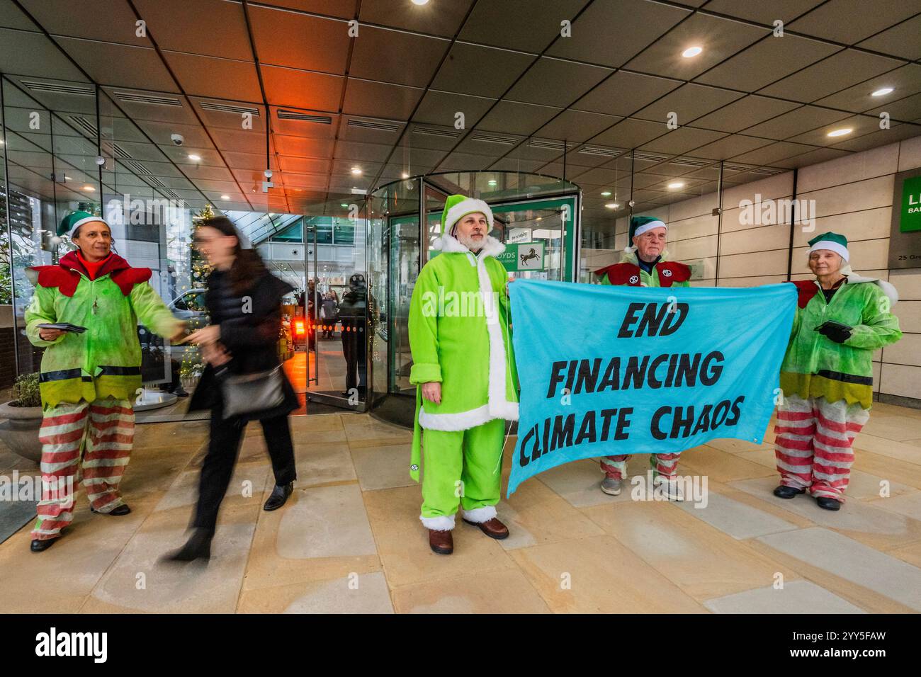Londres, Royaume-Uni. 19 décembre 2024. Une rébellion d'extinction Green Santa et ses elfes piquèrent l'entrée principale et distribuèrent des tracts pour demander à Lloyds Bank de «nettoyer leur acte!» et pour mettre fin au financement du chaos climatique. Les manifestants pensent que Lloyds pourrait être un leader sur le climat, mais « ne prennent pas les mesures nécessaires ». La manifestation a eu lieu devant le siège de la Banque à Gresham Street, dans la ville de Londres. Crédit : Guy Bell/Alamy Live News Banque D'Images