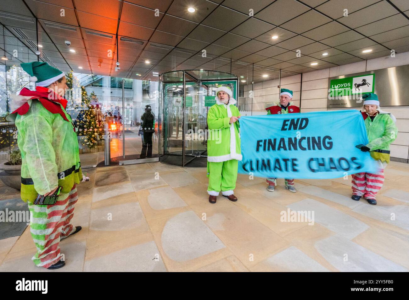 Londres, Royaume-Uni. 19 décembre 2024. Une rébellion d'extinction Green Santa et ses elfes piquèrent l'entrée principale et distribuèrent des tracts pour demander à Lloyds Bank de «nettoyer leur acte!» et pour mettre fin au financement du chaos climatique. Les manifestants pensent que Lloyds pourrait être un leader sur le climat, mais « ne prennent pas les mesures nécessaires ». La manifestation a eu lieu devant le siège de la Banque à Gresham Street, dans la ville de Londres. Crédit : Guy Bell/Alamy Live News Banque D'Images