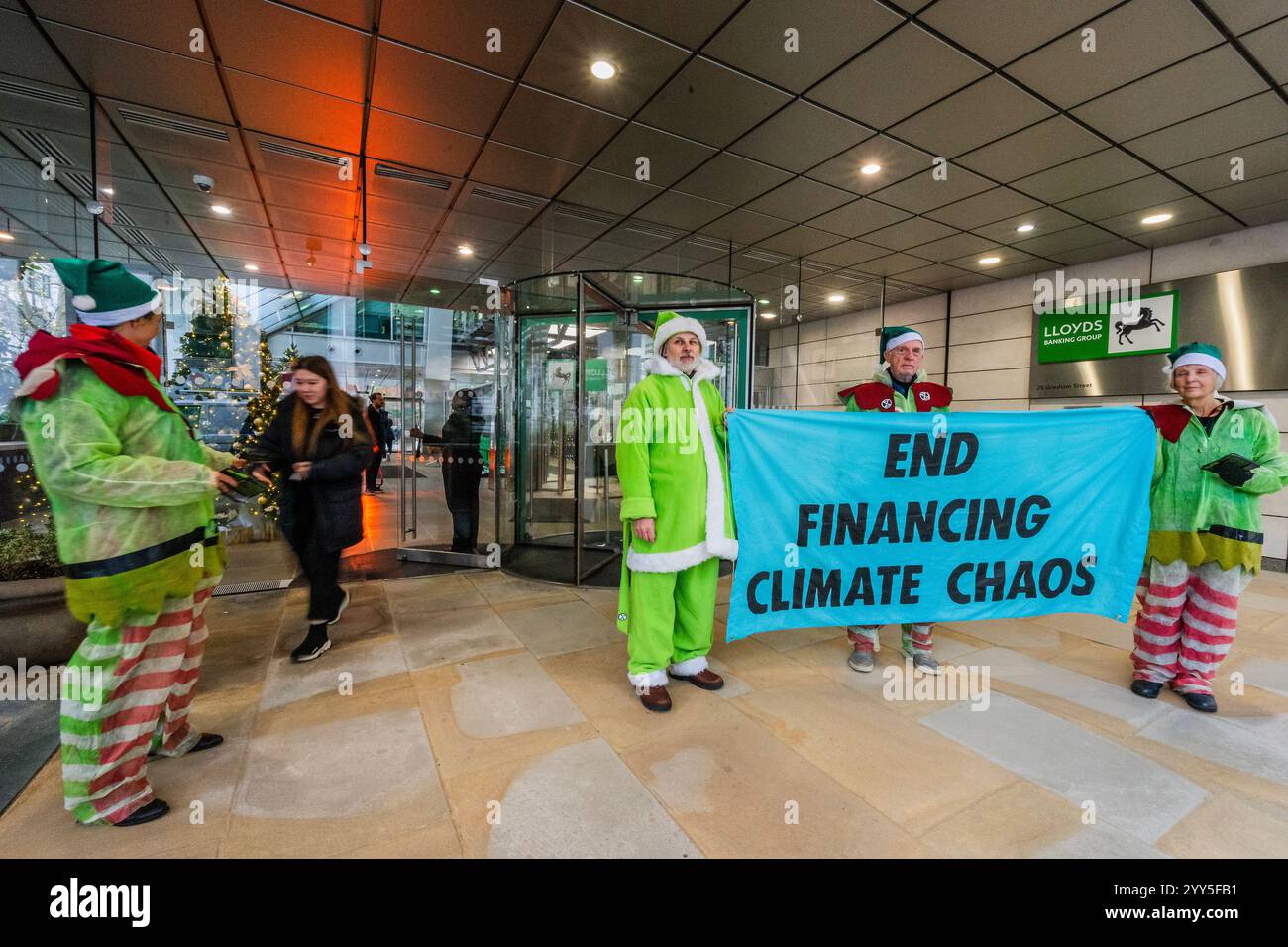 Londres, Royaume-Uni. 19 décembre 2024. Une rébellion d'extinction Green Santa et ses elfes piquèrent l'entrée principale et distribuèrent des tracts pour demander à Lloyds Bank de «nettoyer leur acte!» et pour mettre fin au financement du chaos climatique. Les manifestants pensent que Lloyds pourrait être un leader sur le climat, mais « ne prennent pas les mesures nécessaires ». La manifestation a eu lieu devant le siège de la Banque à Gresham Street, dans la ville de Londres. Crédit : Guy Bell/Alamy Live News Banque D'Images